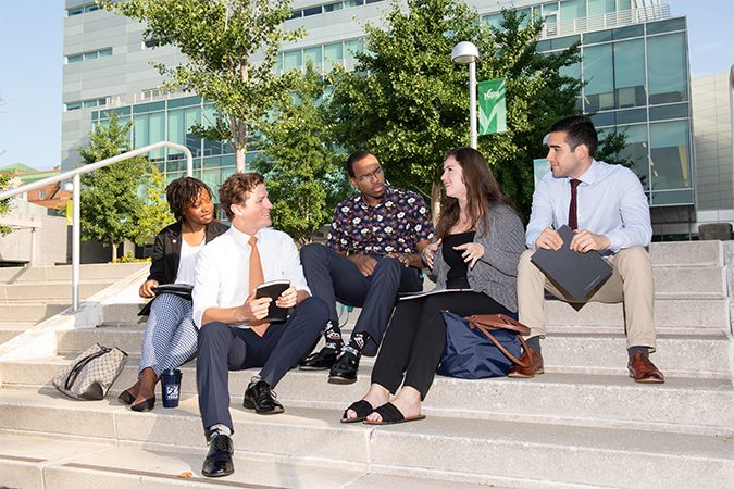 Students sitting on steps of GMU building after class.